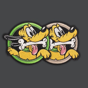Pode incluir: Patches bordados com um cão de desenho animado amarelo com um osso na boca. O cão está dentro de uma moldura circular verde e castanha. O cão tem um nariz preto, olhos brancos e uma língua rosa.