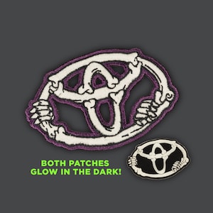 Puede incluir: Dos parches bordados con un logotipo de Toyota esqueletizado. El parche más grande tiene un contorno morado y el parche más pequeño tiene un contorno negro. Ambos parches brillan en la oscuridad. "BOTH PATCHES GLOW IN THE DARK!" está escrito en texto verde debajo de los parches.