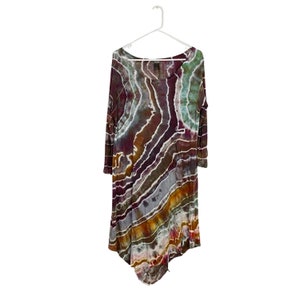 May include: A long-sleeved, tie-dye dress with a flowing, asymmetrical hemline. The dress features a swirling pattern of purple, brown, green, and orange.