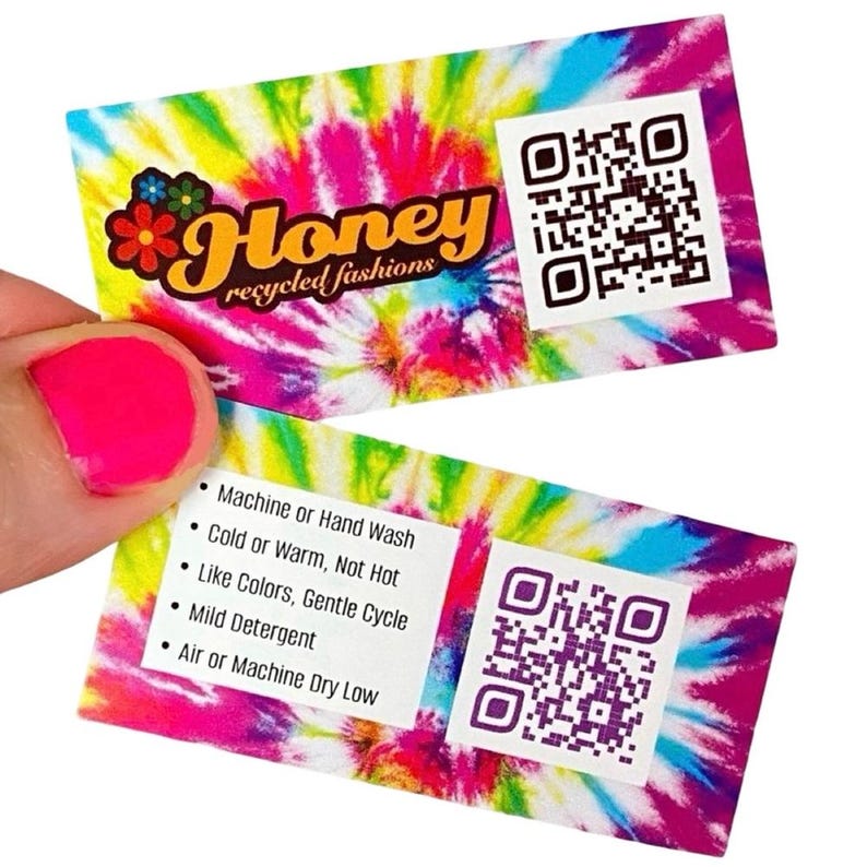 May include: Two colourful tie-dye fabric care labels with a QR code on each. The text on the label reads "Honey recycled fashions" and includes care instructions: Machine or Hand Wash, Cold or Warm, Not Hot, Like Colours, Gentle Cycle, Mild Detergent, Air or Machine Dry Low.
