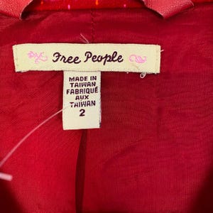 May include: A red and white patterned jacket with a Free People label. The label says "Made in Taiwan Fabriqu&eacute; aux Taiwan 2".