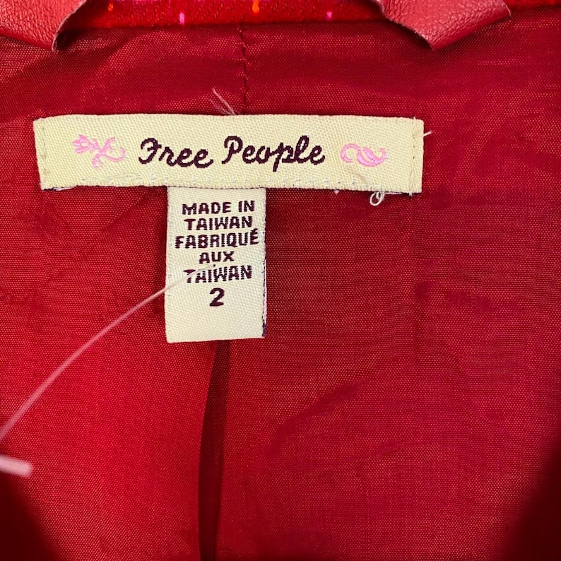 May include: A red and white patterned jacket with a Free People label. The label says "Made in Taiwan Fabriqu&eacute; aux Taiwan 2".