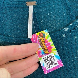 May include: A teal blue waffle knit top with a white tag that says "Free People" and a pink and green tag that says "Honey recycled fashions" with a QR code.