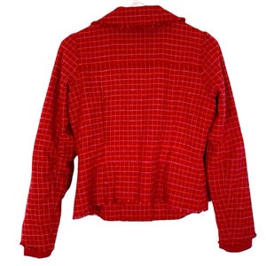 May include: A red tweed blazer with a checkered pattern. The blazer has a collar and long sleeves.