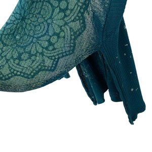 May include: Teal blue waffle knit sweater with a faded mandala design. The sweater has a relaxed fit and a slightly cropped length.