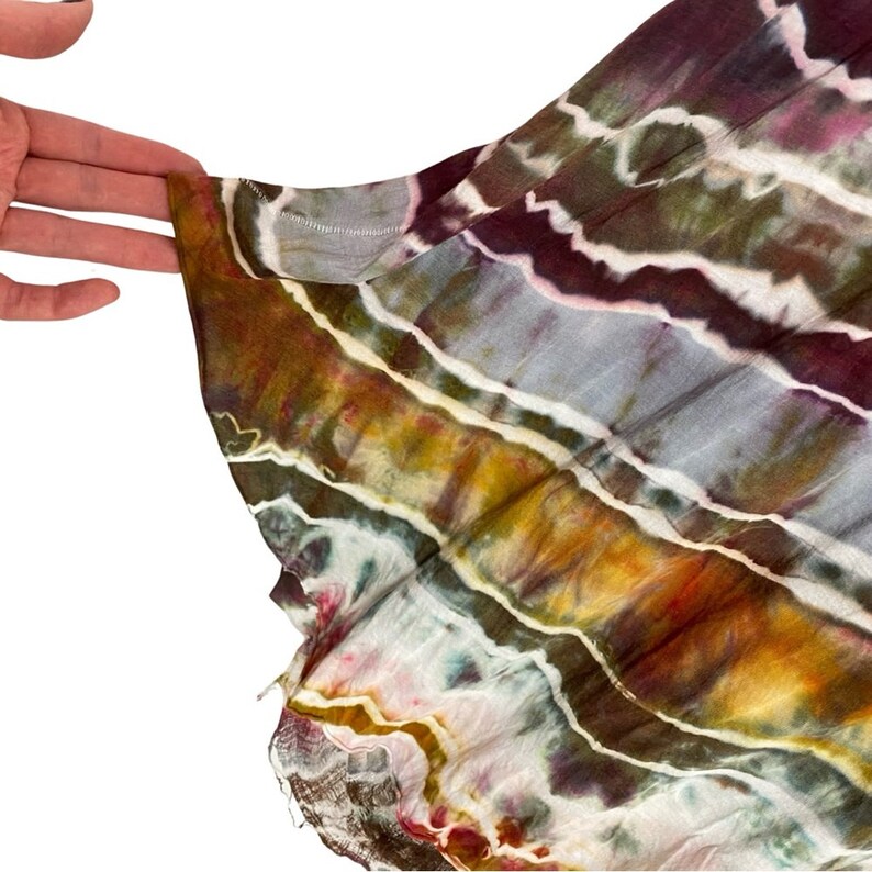 May include: A close-up of a tie-dye fabric with a striped pattern in shades of brown, green, purple, and white.