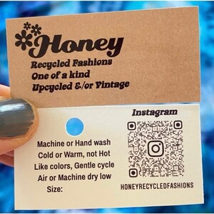 May include: A business card for *Honey Recycled Fashions* with the text "One of a kind Upcycled &/or Vintage" and a QR code for their Instagram page. The card also includes care instructions for the clothing: Machine or Hand wash Cold or Warm, not Hot Like colors, Gentle cycle Air or Machine dry low Size: