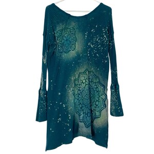 May include: Teal blue waffle knit long-sleeved shirt with a white bleached effect and two green mandala designs.