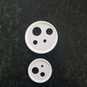May include: Two white plastic cookie cutters, one larger than the other, with various sized circles cut out.