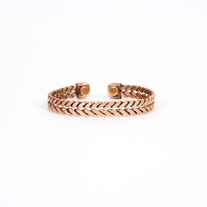 May include: A copper bracelet with a braided design and magnetic closures.