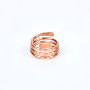 May include: A copper ring with a spiral design. The ring is made of multiple coils of wire that are twisted together.
