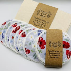 May include: Washable makeup remover pads with a floral design of red poppies and white flowers on a light blue fabric. The pads are presented with a beige cloth and a brown label that reads "Gracie Goes Green".