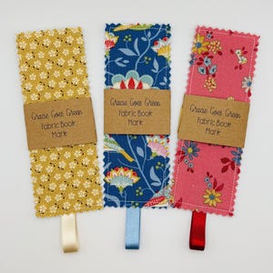 May include: Three fabric bookmarks with different patterns. Each bookmark has a brown tag with the text "Gracie Goes Green Fabric Book Mark". The bookmarks are yellow with a white floral pattern, blue with a floral pattern, and pink with a floral pattern.