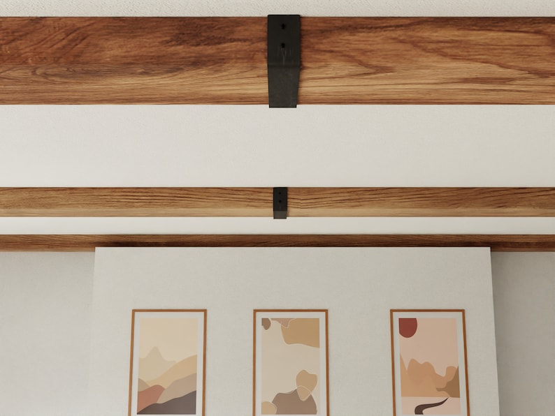 May include: Three framed abstract art prints with muted colours and geometric shapes hang on a white wall beneath a wooden beam ceiling.