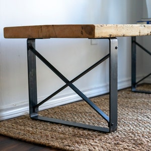Könnte beinhalten: Ein Holz-Couchtisch mit einer natürlichen Holzoptik und schwarzen Metallbeinen. Die Beine haben ein Kreuzdesign.