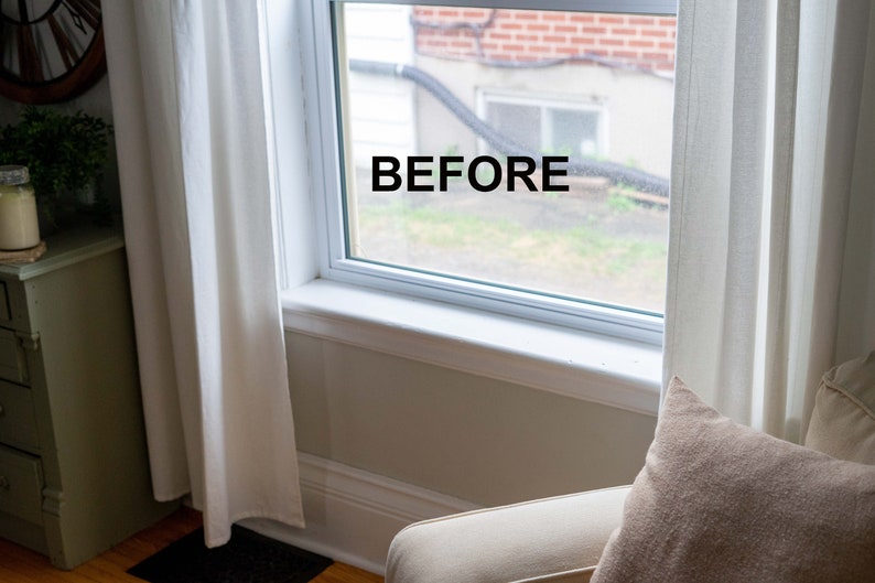 May include: A white window with white trim and a view of a brick building and green grass. The word "BEFORE" is written on the window.