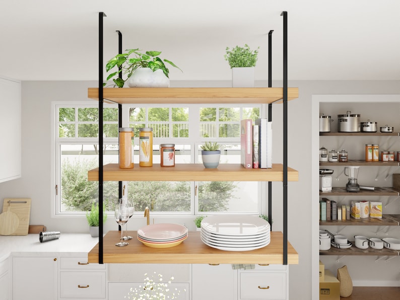 May include: A wooden shelf unit with black metal supports hangs from the ceiling. The shelves are filled with plants, jars, and books. The unit is in a kitchen setting.