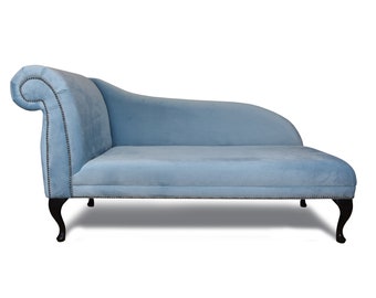 Könnte beinhalten: Eine hellblaue Chaiselongue mit einer geschwungenen Rückenlehne und Holzbeinen. Die Chaiselongue ist mit einem weichen Stoff bezogen und hat ein gestepptes Design.