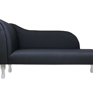 May include: A black chaise longue with white wooden legs. The chaise longue has a curved back and a tufted seat.