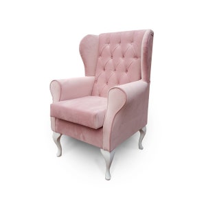 May include: A pink velvet armchair with a tufted back and white wooden legs. The chair has a classic design and is perfect for adding a touch of elegance to any room.
