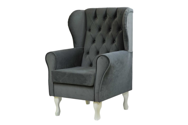 May include: A gray upholstered armchair with a tufted back and white wooden legs. The chair has a high back and wing-like sides.