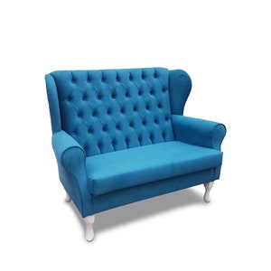 May include: A blue tufted loveseat with a high back and white legs. The loveseat is upholstered in a soft, plush fabric.