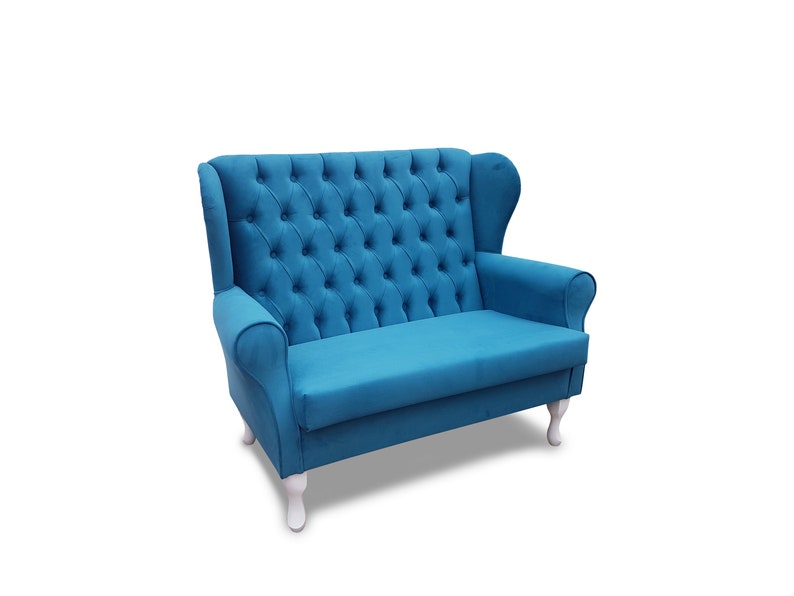 May include: A blue tufted loveseat with a high back and white legs. The loveseat is upholstered in a soft, plush fabric.