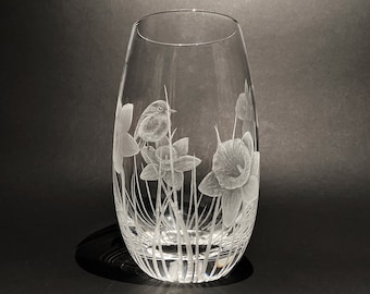 May include: A clear glass vase with an etched design of daffodils and a robin. The vase has a rounded bottom and a cylindrical top.