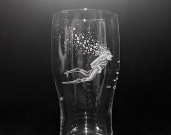Puede incluir: Un vaso de pinta de vidrio transparente con un diseño grabado de un buceador con burbujas que suben a su alrededor.