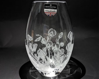 May include: A clear glass vase with an etched design of white sweet peas. The vase has a label that reads "Dartington Crystal Handmade".