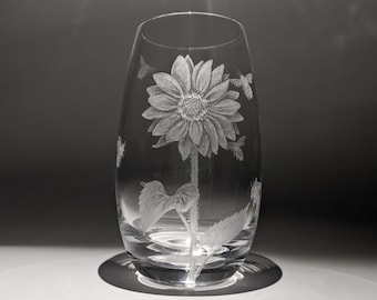 May include: A clear glass vase with an etched design of a sunflower and bees. The vase is round and has a wide mouth.