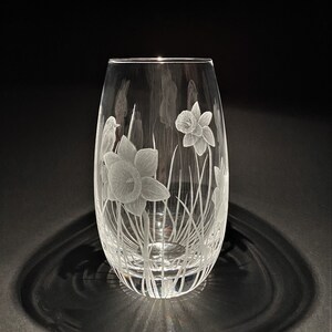 K&ouml;nnte beinhalten: Eine klare Glasvase mit einem ge&auml;tzten Design aus Narzissen und einem Vogel. Die Vase ist oval geformt und hat eine schmale &Ouml;ffnung.