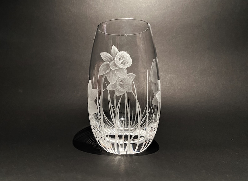 K&ouml;nnte beinhalten: Eine klare Glasvase mit einem gravierten Design aus wei&szlig;en Narzissen.