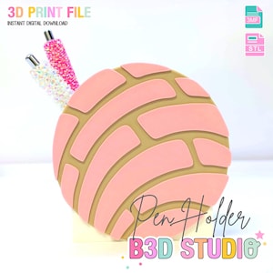 May include: A pink pen holder shaped like a concha pastry, with a light brown interior. Two decorative pens with glitter are in the holder. The text "Pen Holder" and "B3D STUDIO" are visible.