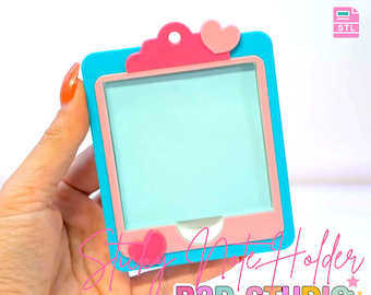 May include: A blue and pink 3D-printed art holder with a heart-shaped accent. The holder has a rectangular frame with a light blue interior. Text on the image reads "3D PRINT FILE" and "B3D STUDIO".