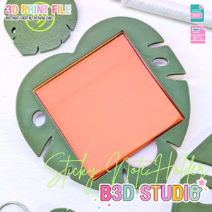 May include: A green, leaf-shaped sticky note holder with an orange note pad. The holder has a heart-like shape with cut-out details. The text "Sticky Note Holder" and "B3D STUDIO" are visible.