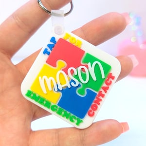 May include: A colorful puzzle-piece keychain with the name "Mason" in white script. The keychain has a metal ring and a plastic clasp. The words "TAP FOR EMERGENCY CONTACT" are printed around the edges of the puzzle pieces.