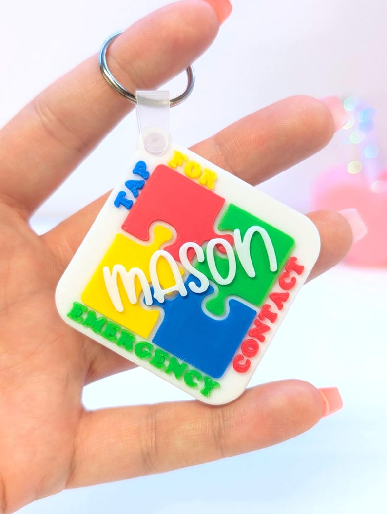 May include: A colorful puzzle-piece keychain with the name "Mason" in white script. The keychain has a metal ring and a plastic clasp. The words "TAP FOR EMERGENCY CONTACT" are printed around the edges of the puzzle pieces.