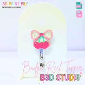 May include: A pink and green cherry-shaped badge reel topper with a bow design. The topper is attached to a clear plastic reel with a metal clip. Text on the image reads "3D PRINT FILE" and "INSTANT DIGITAL DOWNLOAD". The words "Badge Reel Topper" and "B3D STUDIO" are also visible.