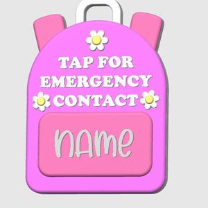 May include: A pink backpack-shaped tag with white text that reads "TAP FOR EMERGENCY CONTACT" and "NAME". The tag has a white handle and two pink side pockets. It is decorated with three yellow and white flower accents.