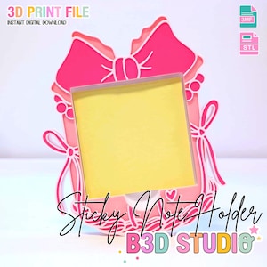 Puede incluir: Un soporte para notas adhesivas rosa y blanco impreso en 3D con forma de lazo, con un bloc de notas adhesivas amarillo en el interior. El texto "3D PRINT FILE" e "INSTANT DIGITAL DOWNLOAD" están en la parte superior. También se ven las palabras "Sticky Note Holder" y "B3D STUDIO".