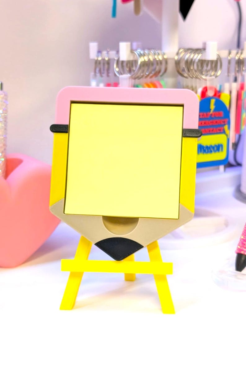 May include: A yellow pencil-shaped desk organizer with a pink top and a yellow easel base. The organizer has a yellow notepad and a small drawer. The design includes black and tan accents. The word "Mason" is visible on a sticker.