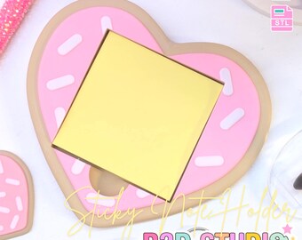 May include: A heart-shaped sticky note holder designed to resemble a donut. The holder is pink with white sprinkles and a yellow sticky note pad. Text on the image reads "3D PRINT FILE" and "INSTANT DIGITAL DOWNLOAD". The text "Sticky Note Holder" and "B3D STUDIO" are also visible.