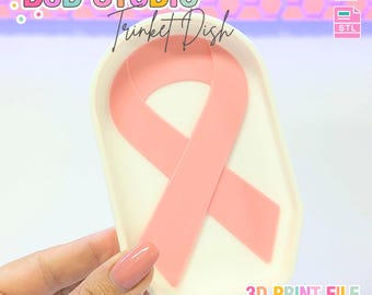May include: A white trinket dish with a pink ribbon design. The dish has a rectangular shape with rounded corners. The text "B3D STUDIO" and "Trinket Dish" are visible. The words "3D PRINT FILE" and "INSTANT DIGITAL DOWNLOAD" are also present.