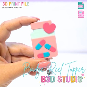 Puede incluir: Un adorno de carrete de insignia rosa con forma de frasco de pastillas con un corazón rosa y tres pastillas. El adorno tiene el texto "3D PRINT FILE" y "INSTANT DIGITAL DOWNLOAD". También se ve el texto "Badge Reel Topper" y "B3D STUDIO".