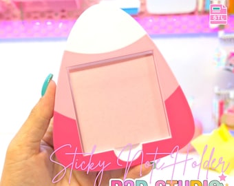 May include: A pink and white sticky note holder with a rectangular opening. The holder has a rounded top and is labeled "Sticky Note Holder" and "B3D STUDIO". The image also includes the text "3D PRINT FILE" and file type icons.