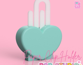Puede incluir: Un sujetapapeles en forma de corazón de color turquesa claro con detalles blancos. El soporte tiene un asa curvada y dos postes verticales. El texto "Paper Clip Holder" y "B3D STUDIO" está presente. La imagen también dice "3D PRINT FILE" y "INSTANT DIGITAL DOWNLOAD".