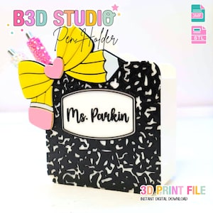 Puede incluir: Un portalápices impreso en 3D con forma de cuaderno de composición, con un diseño de lápiz y lazo. El soporte es blanco y negro con el nombre "Ms. Parkin" en la parte delantera. El texto "B3D STUDIO Pen Holder" está en la parte superior.