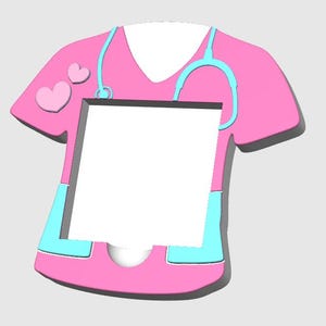 Op de afbeelding: Roze medische scrubs met een stethoscoopontwerp en twee harten op de schouder. De scrubs hebben een lichtblauwe rand en een groot wit vierkant in het midden. Een decoratief item met een medisch thema.