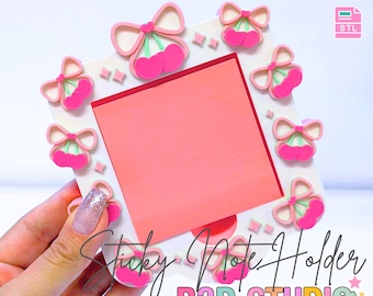 Peut inclure: Un porte-bloc-notes carré avec une note rose et des décorations de cerises et de nœuds. Le support est blanc avec des cerises et des nœuds roses et verts sur les bords. Le texte indique "Sticky Note Holder" et "B3D STUDIO".